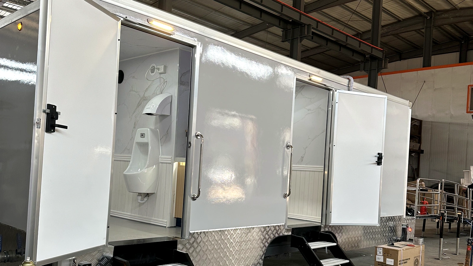 2 stall plus ADA family restroom trailer with men’s room, women’s room, accessible family restroom, and long ramp system in factory production.