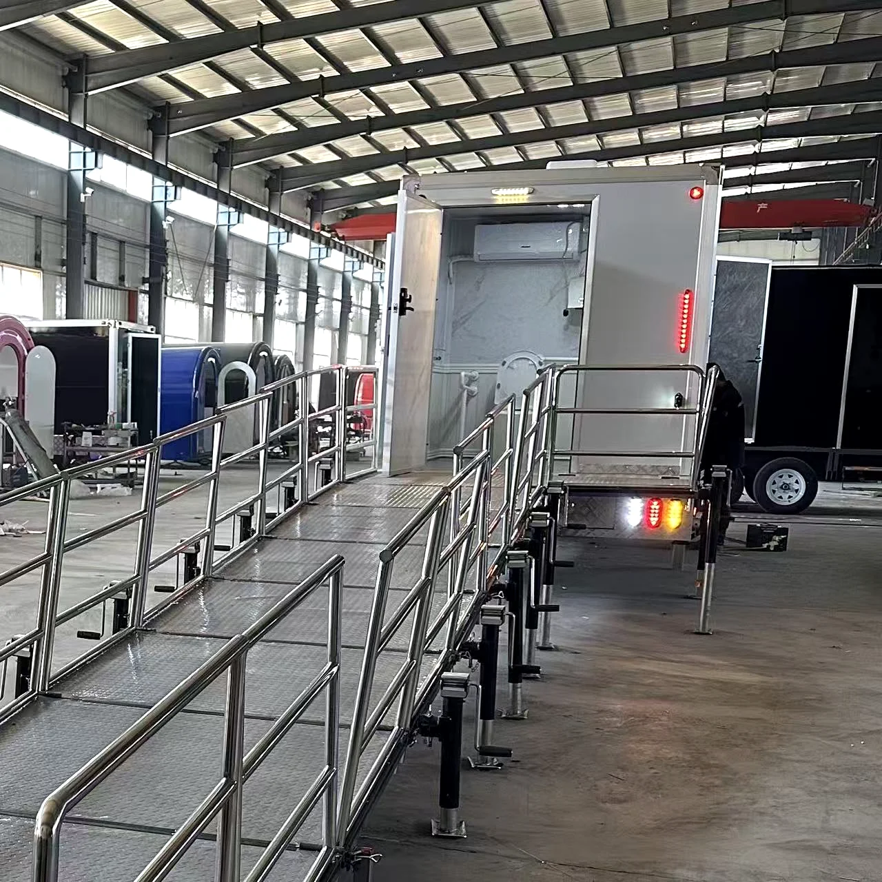 ADA family restroom trailer interior with toilet, grab bars, sink, mirror, baby changing station, and spacious accessible layout.