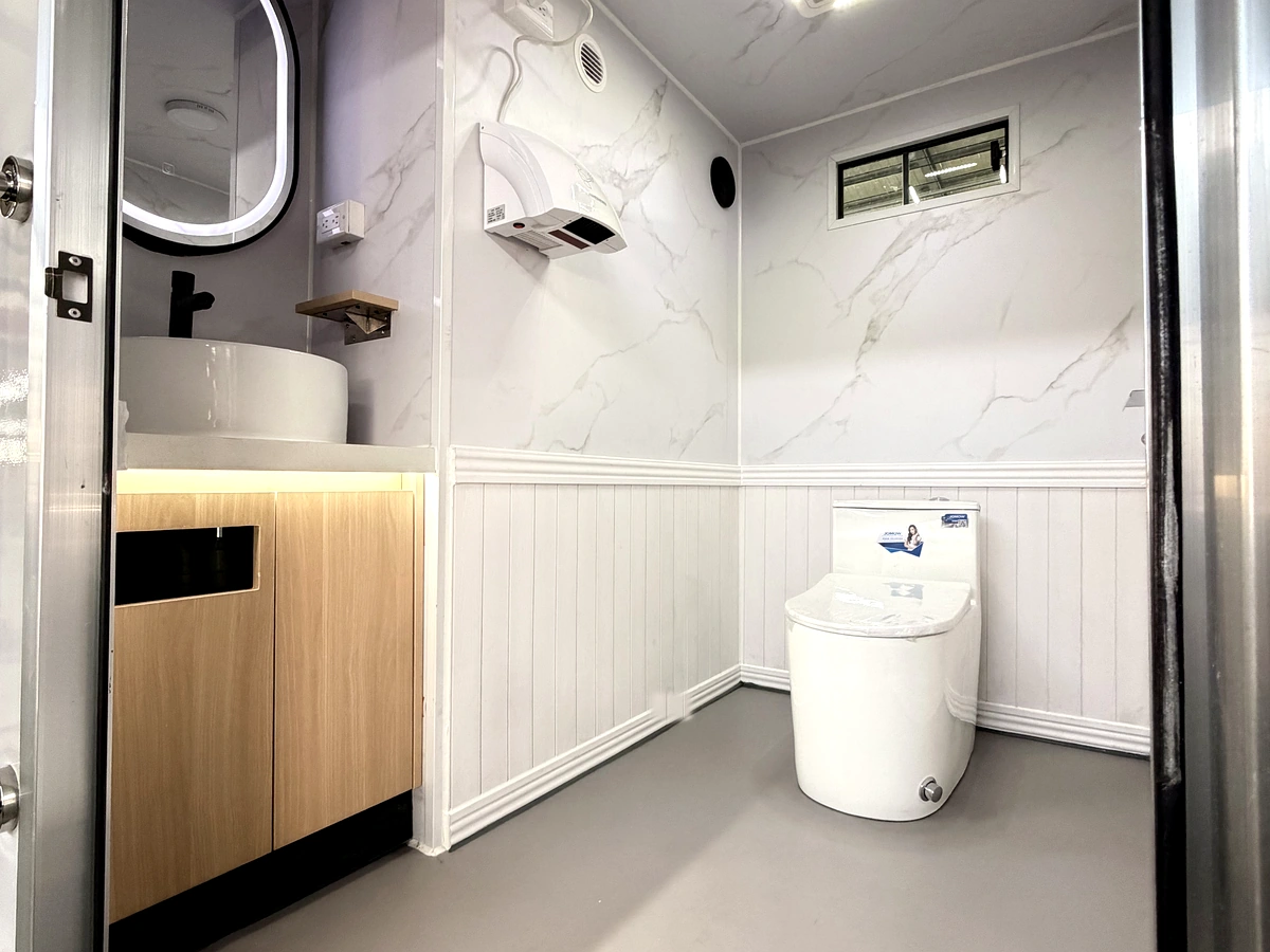 Women’s room interior of 2 stall plus ADA restroom trailer with toilet, sink, mirror, cabinet, and hand dryer